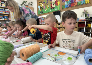 05 Dzieci przy stolikach ucinają kolorowe sznurki z panią