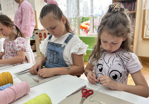 02 Dziewczynki przy stoliku nakładają koraliki z literkami na sznurki
