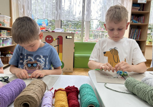 03 Chłopcy nakładają szydełkami koraliki z literkami na sznurki