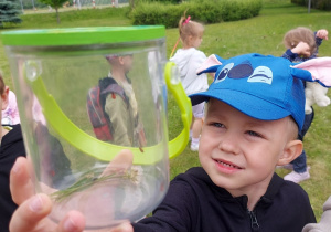 Chłopiec pokazuje znalezionych mieszkańców łąki umieszczonych w specjalnym pojemniku do obserwacji