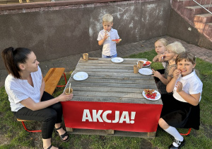 Dzieci jedzą kiełbaskę z grilla