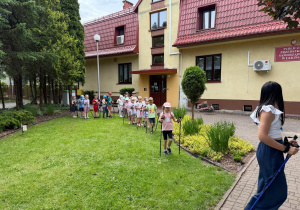 Dzieci idą z kijami za panią.