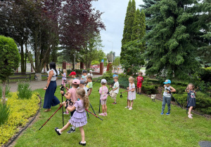 Dzieci wykonują ćwiczenia z użyciem kijków.