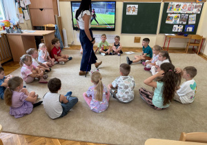 Pani pokazuje dzieciom prawidłową technikę chodzenia z kijkami.