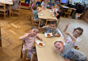 Dzieci zjadają wspólnie pizzę.