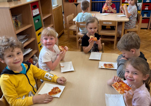 Dzieci zjadają wspólnie pizzę.
