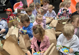 16 Dzieci z grupy trzylatków oglądają nagrody siedząc na kocu