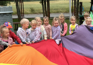 19 Uśmiechnięte dzieci z grupy trzylatków trzymają chustę animacyjną