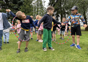 32 Chłopcy przechodzą przez hula hop trzymając się za ręce