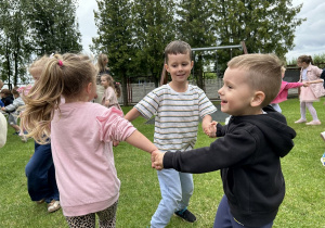 34 Troje dzieci tańczy trzymając się za ręce