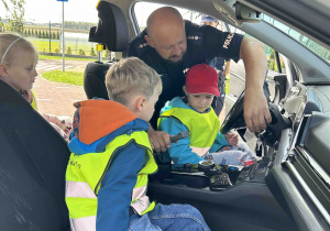 Pan Policjant pokazuje dzieciom auto.