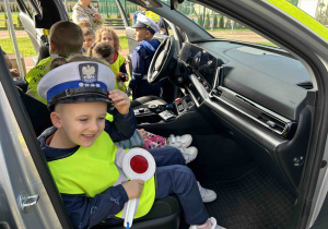 Chłopiec w czapce policjanta w aucie.