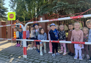 Dzieci za barierką na skrzyżowaniu.
