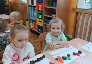 25. Dziewczynki ułożyły na kartce kasztany i liście.