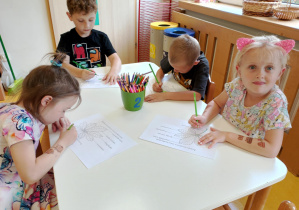 Dzieci kolorują kredkami.