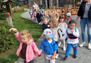 Przedszkolaki ustawione w parach idą do mini zoo.
