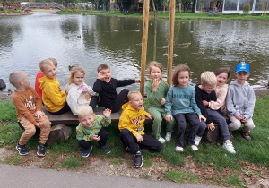 Zadowolone przedszkolaki siedzą na ławce.