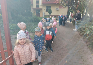 Dzieci ustawione w pary stoją przed przedszkolem.