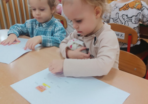 Dziewczynka wkleja ilustrację Śmieszki do książeczki