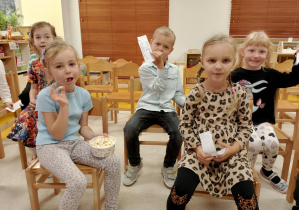 Dzieci jedzą popcron.