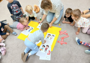 Chłopczyk przykleja ilustracje na plakacie