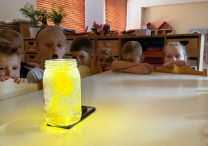 Zdziwione dzieci obserwują eksperyment.
