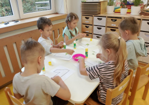 Dzieci wykonują pracę plastyczną z cyfrą 1.