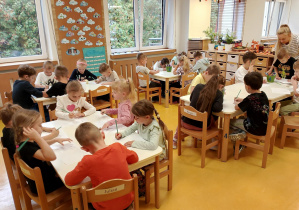 Dzieci piszą cyfrę 1 przy stoliczkach.