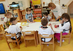 Dzieci z panią dietetyk przygotowują zdrową przekąskę.