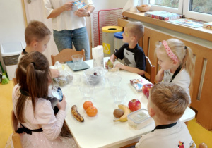 Pani sprawdza skład przekąsek przyniesionych przez dzieci.