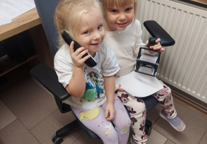 Dziewczynki pozują do zdjęcia z telefonem i pieczątką.