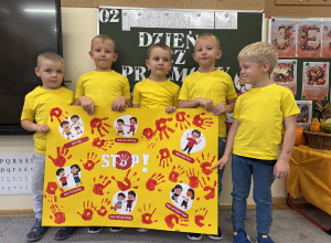 Dzieci ubrane w zółte koszulki trzymają plakat Stop Przemocy