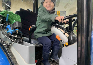 Chłopiec siedzi w traktorze.