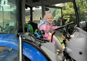 Dziewczynka siedzi w traktorze.