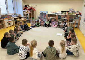 Dzieci siedzą w kole na dywanie.