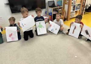 Chłopcy pokazują narysowane stworki.