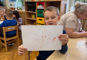 Chłopiec prezentuje swój rysunek.