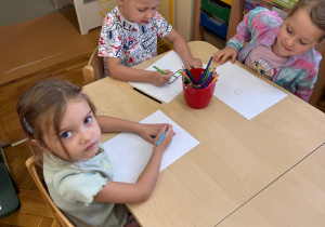 Dzieci rysują wspólnie przy stoliczku.