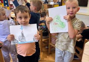 Chłopcy prezentują swoje rysunki.