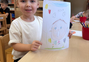 Dziewczynka prezentuje swój rysunek.