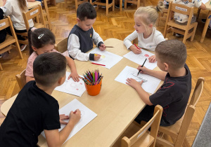 Dzieci rysują przy stoliczkach.