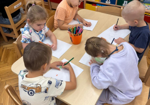 Dzieci rysują przy stoliczkach.