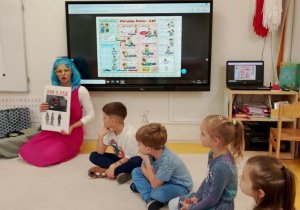 Pani prezentuje dzieciom numery alarmowe.