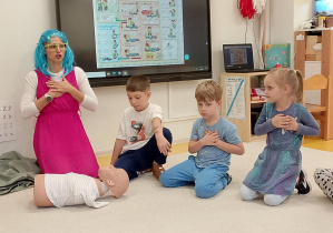 Pani pokazuje jak należy uciskać klatkę piersiową.