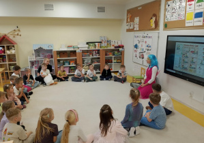 Dzieci siedzą w kole i słuchają Pani ratownik.