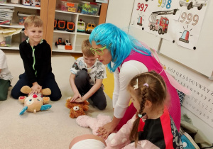 Dziewczynka przebrana za ratownika uczy się udzielania pierwszej pomocy.