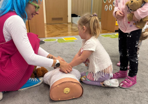 Dziewczynka uczy się prawidłowej techniki ucisków.