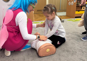 Dziewczynka uczy się prawidłowej techniki ucisków.