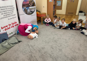 Pani prezentuje na manekinie jak udzielić pierwszej pomocy.