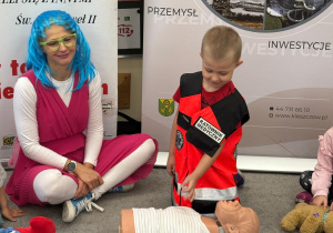 Chłopiec przebrany w strój ratownika udziela pierwszej pomocy.